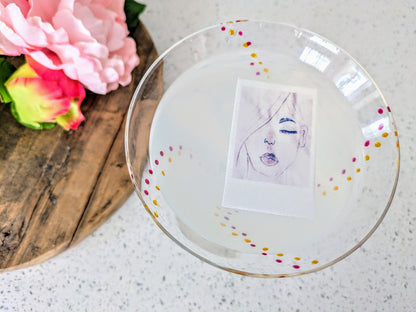 A custom edible image drink topper with a photograph printed on it, placed on a glass filled with a cocktail beverage