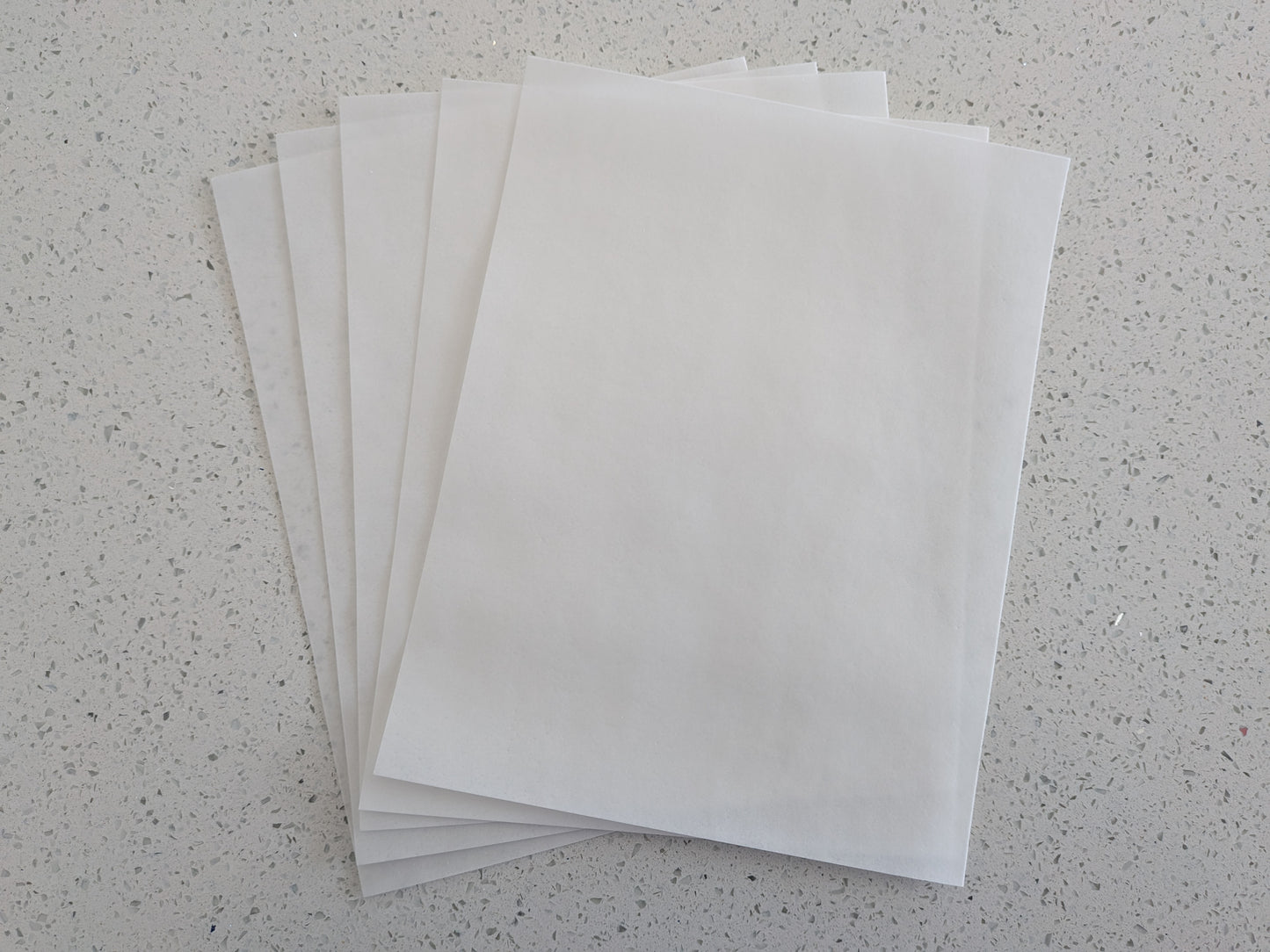 Stack of edible wafer paper sheets on a speckled gray surface