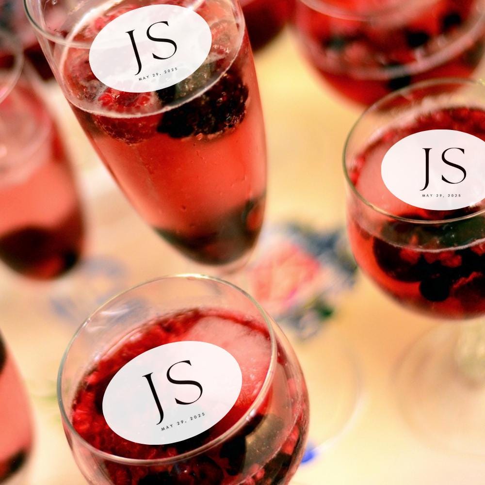 Glasses of red beverage with edible drink garnish 'JS' labels on a blurred background