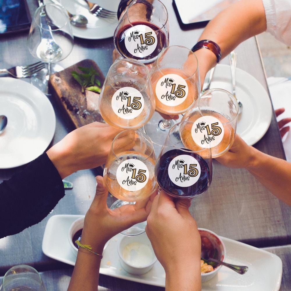 People holding glasses with 'Mis 15 Años' drink garnish at a celebratory meal.