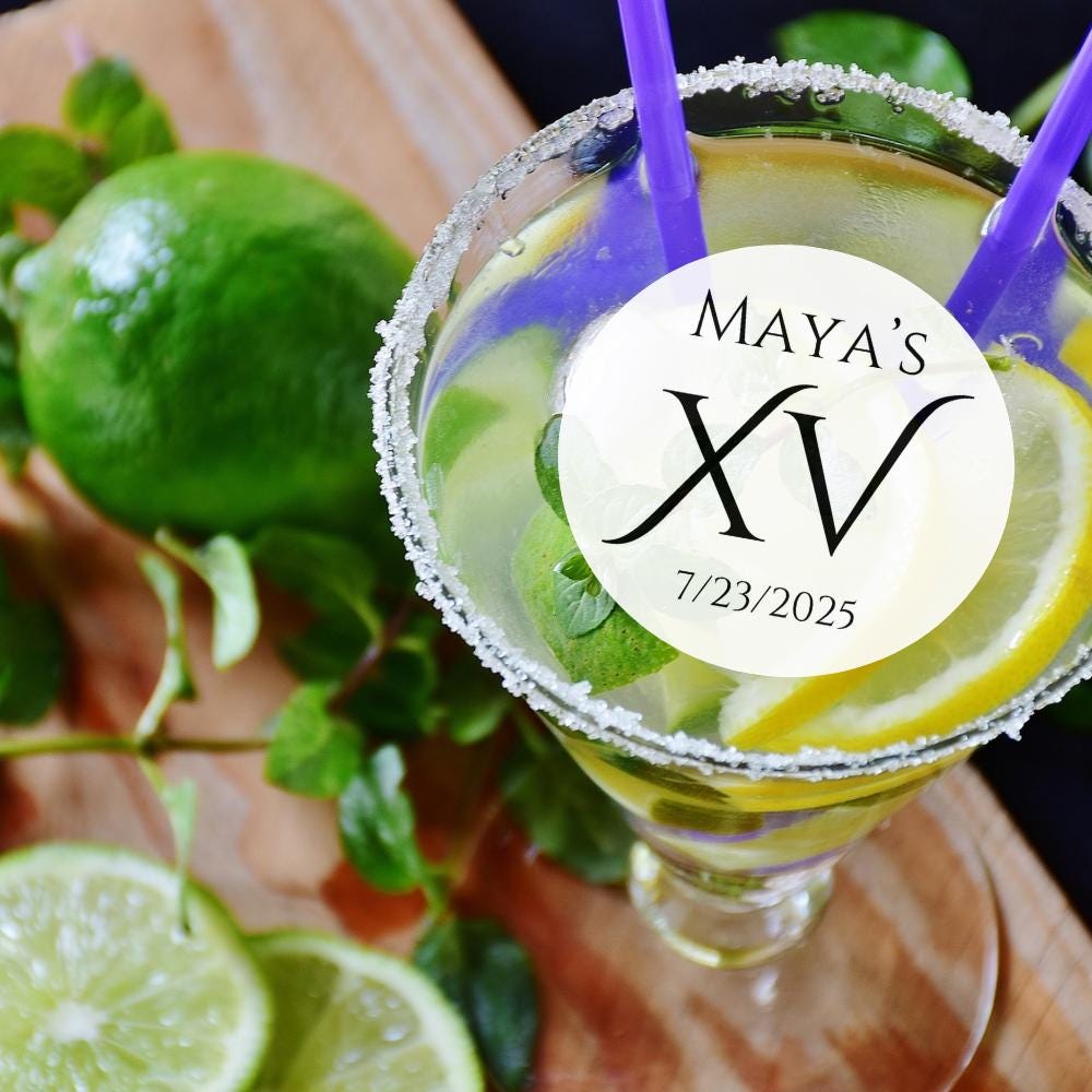 Margarita with a 'MAYA'S XV' birthday mocktail garnish on a wooden surface with limes and mint.