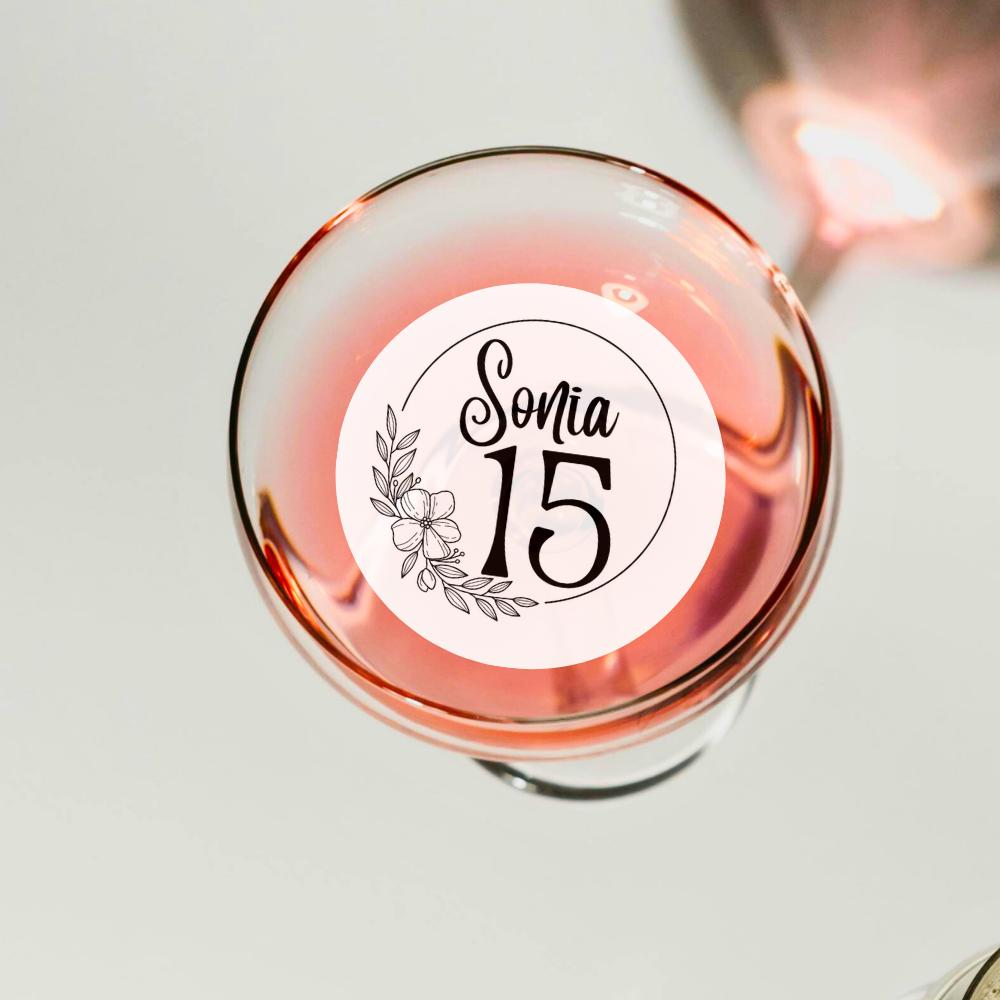 Glass of pink wine with a decorative cocktail garnish topper label on a light background