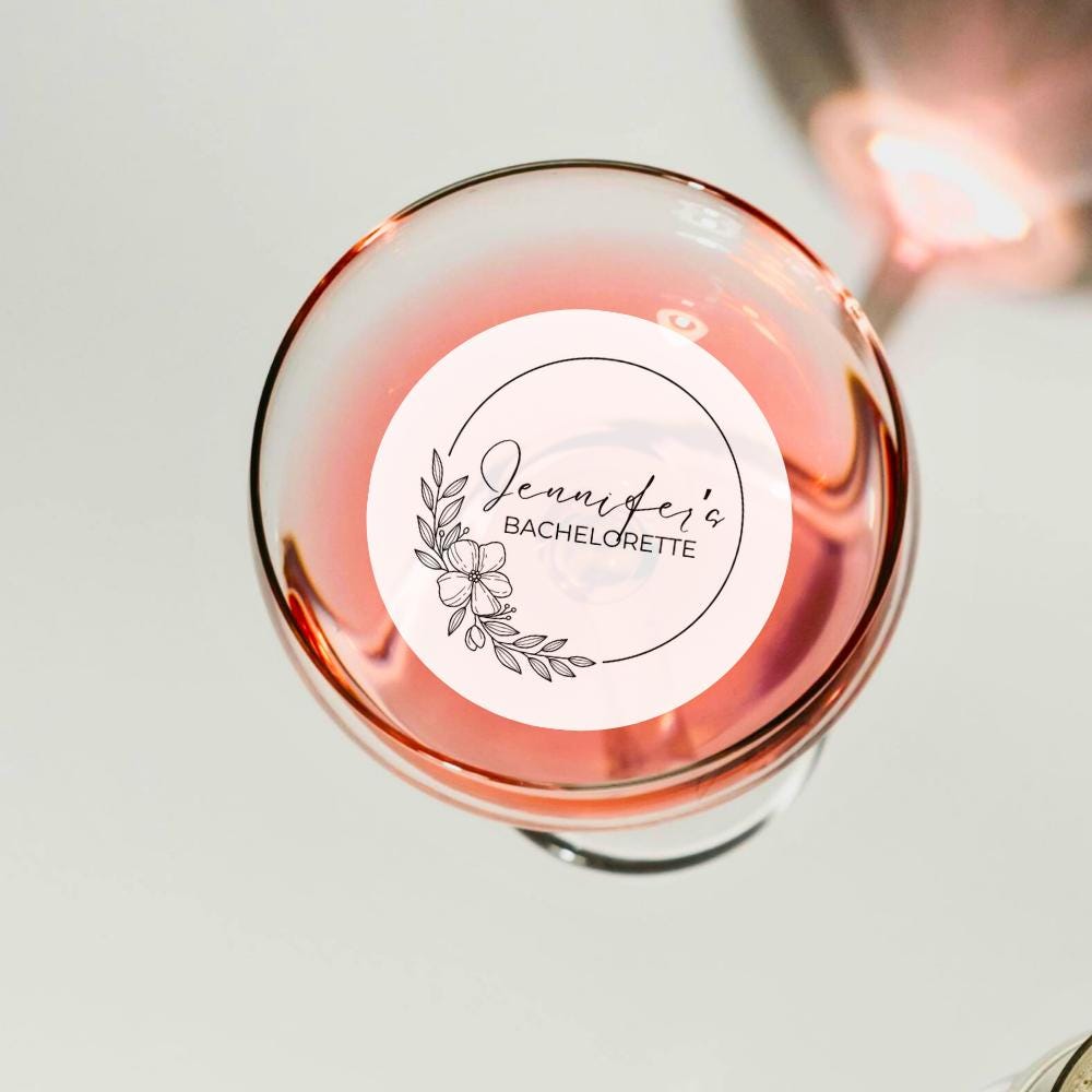 Glass of pink wine with a decorative edible drink topper on a light background