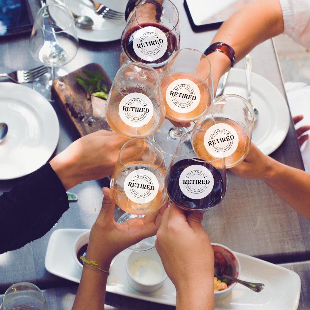 People holding glasses with 'Retired' edible stickers at a dining table.