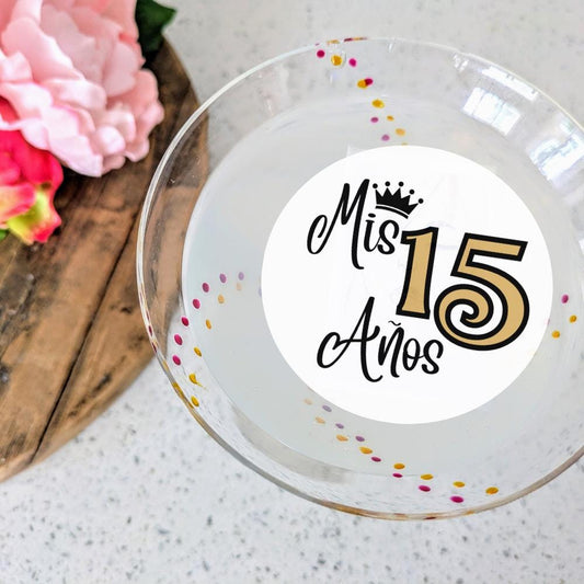 Birthday Quinceañera Drink Topper with 'Mis 15 Años' text on a white surface with flowers.
